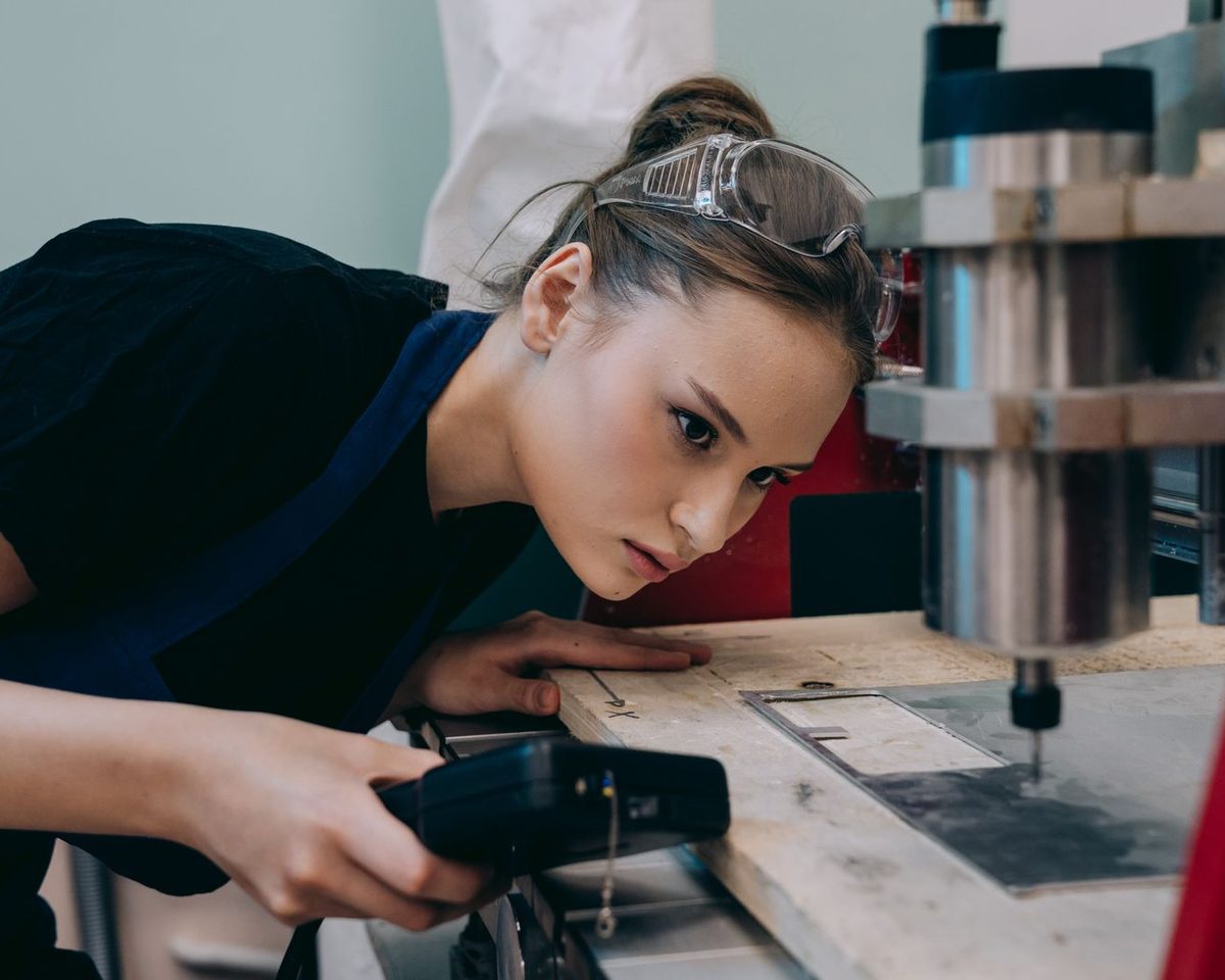 A technician in safety glasses inspecting machinery in a workshop